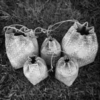 A group of kostat tengguang (lunch bags) woven from åkgak. The larger kostat tengguang on the left and the smaller one just in front of it were woven by Master Weaver Defunta Tan Elena Benavente from the island of Guam, and the remaining three to the right are reproductions of them woven by Chamoru weaver James C. Bamba.